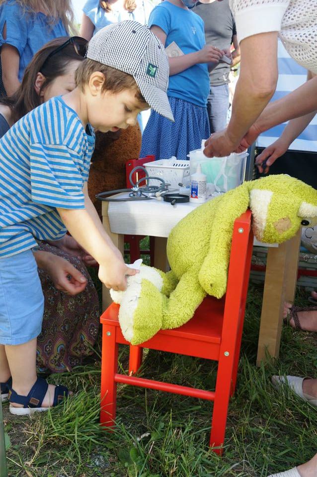 Zabawa w pediatrę - chłopiec nakłada plaster opatrunkowy na skaleczenie żaby-maskotki