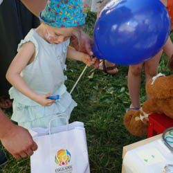 Miniatura: Mała dziewczynka z tatą wyjmuje gadżety z torby z logo przychodni pediatrycznej Eskulapek otrzymane w prezencie podczas festynu